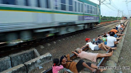 Villagers lie on a railway track for an electricity therapy in Rawa Buaya, Jakarta, Indonesia.