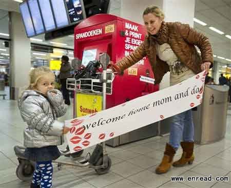 Two-year-old Luna (L) and her aunt hold a banner at Amsterdam Airport Schiphol November 24, 2011.