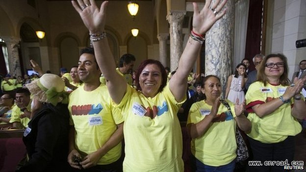 Hotel workers celebrate after the council voted for the hourly wage increase