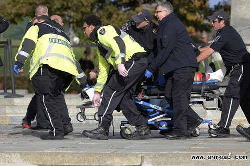 Paramedics and police pull a victim away from the Canadian War Memorial in Ottawa on Wednesday Oct. 22, 2014.